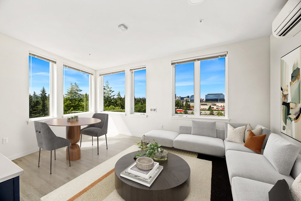 A modern living room with a grey sofa, a coffee table, and a dining table with chairs.